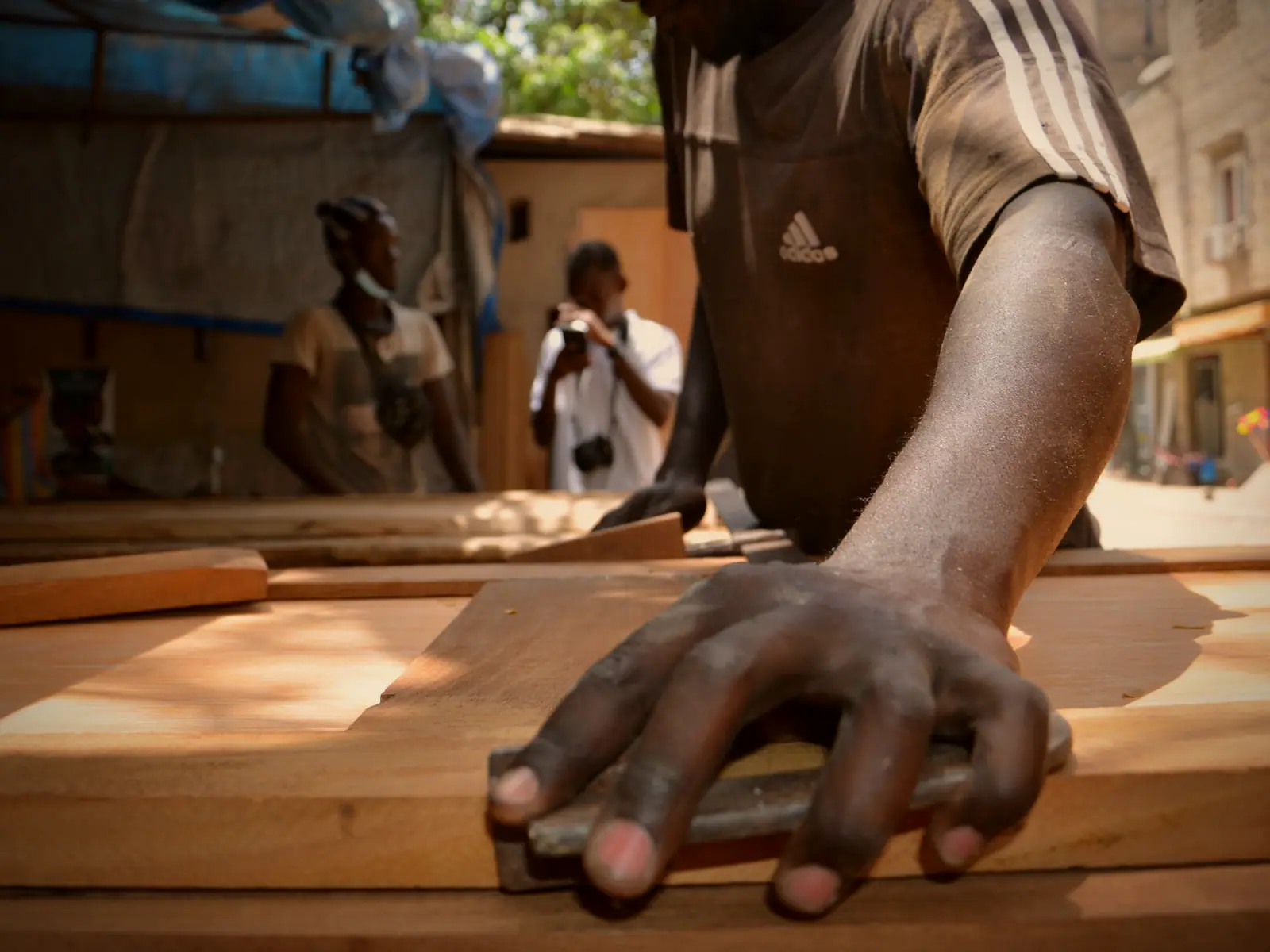 Les mains d'un menuisier guidant une pièce de bois sur un établi.